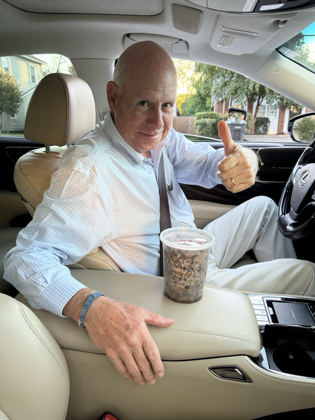 A smiling man giving a thumbs-up beside a cup of boiled peanuts