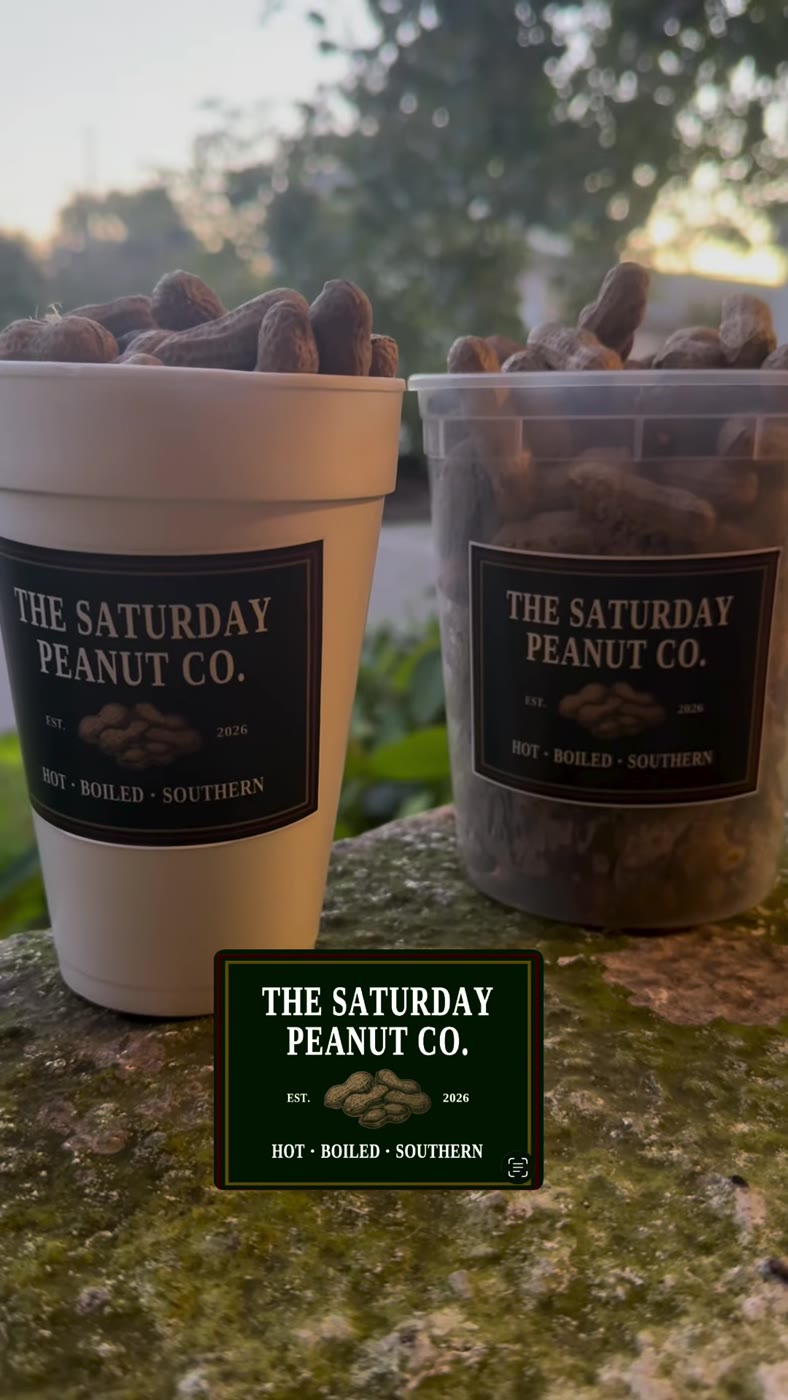 A branded cup and clear container filled with boiled peanuts outside in the sunshine